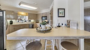 Een moderne keuken met een centraal eiland, ingebouwde apparatuur en een groot raam.