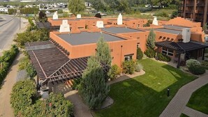 A hotel with a flat roof, a covered outdoor area, and a view of mountains in the background.