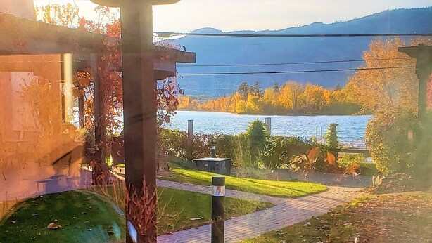 A wooden deck with a view of a lake and autumn foliage.