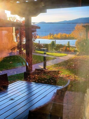 Enjoy a serene view of the water from the deck, surrounded by lush greenery and a rustic pergola.