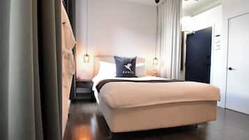 A modern hotel room with a large bed, a nightstand, a desk, and a chair. There is a door and a window in the room.