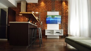 Una cocina moderna con pared de ladrillo, un televisor de pantalla plana y una zona de bar.