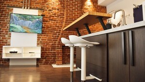Una cocina moderna con pared de ladrillo, encimera de madera y televisor integrado.