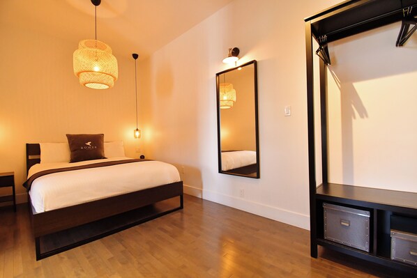 Un dormitorio moderno con cama, lámparas de noche, un espejo grande y suelo de madera.