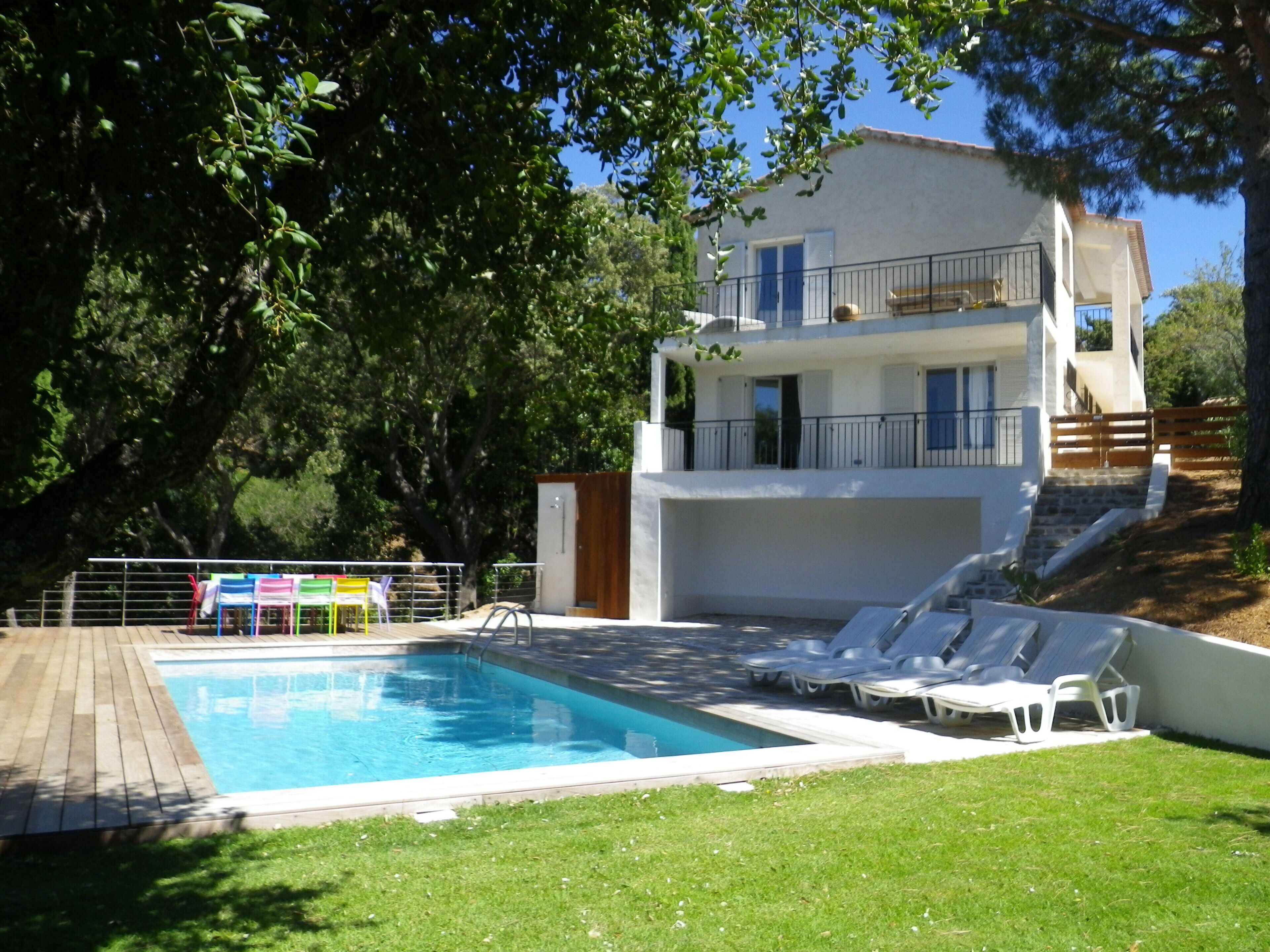 Ein zweistöckiges Gebäude mit Swimmingpool, Außenbereich zum Sitzen und einer Treppe, die zum oberen Stockwerk führt.