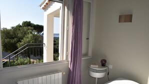 Ein Schlafzimmer mit Fenster, Heizkörper, Nachttisch und Vorhang.