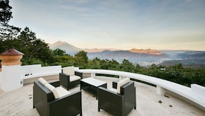 Eine Terrasse im Freien mit Korbmöbeln und Blick auf die Berge.