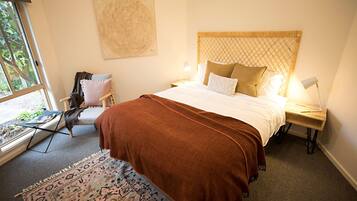A bedroom with a bed, a chair, a table, and a window.