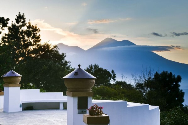 Una terraza con vista a la montaña, paredes blancas y una urna decorativa.