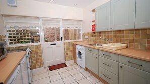 A kitchen with a washing machine, a sink, and cabinets. - Saltburn Holidays Bluebell Cottage (Guisborough)