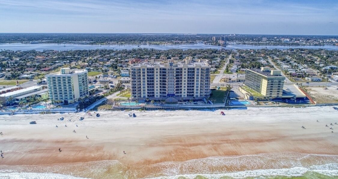 Een strandhotel met meerdere hoge gebouwen, een zandstrand en een uitzicht op de oceaan en de skyline op de achtergrond.