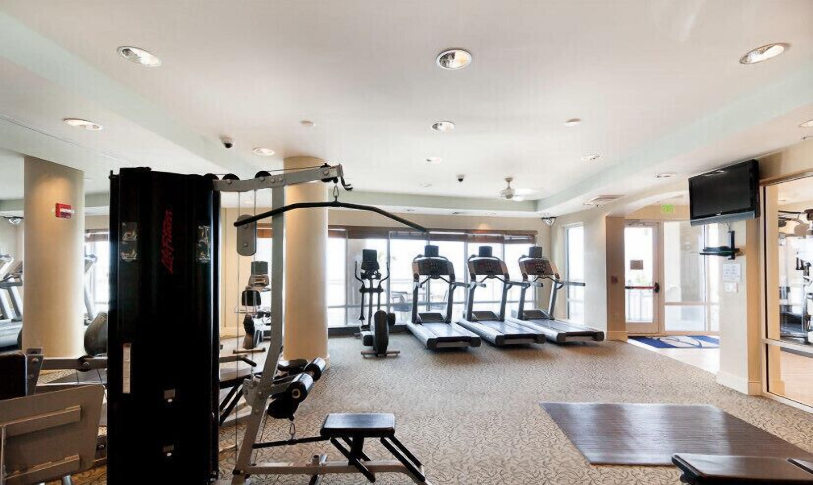Une salle de sport équipée de tapis de course, d’appareils de musculation et d’un sac de frappe.