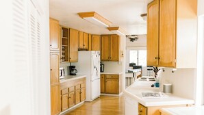 Una cocina con armarios de madera, un refrigerador blanco y una encimera con diversos electrodomésticos.