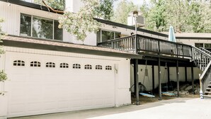 Una casa de dos pisos con un garaje blanco, un porche cubierto con barandilla negra y una escalera que lleva al nivel superior.