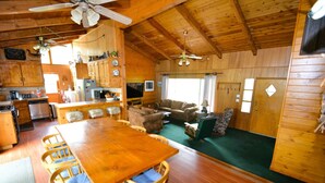 A wooden cabin interior with a dining area, kitchen, and living room. - Johnson Home Lake Front, Boat slip, walking distance to Pines. Takes Pets (Bass Lake)