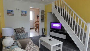 Ein Wohnzimmer mit einer Couch, einem Couchtisch, einem Fernseher und einer Treppe.
