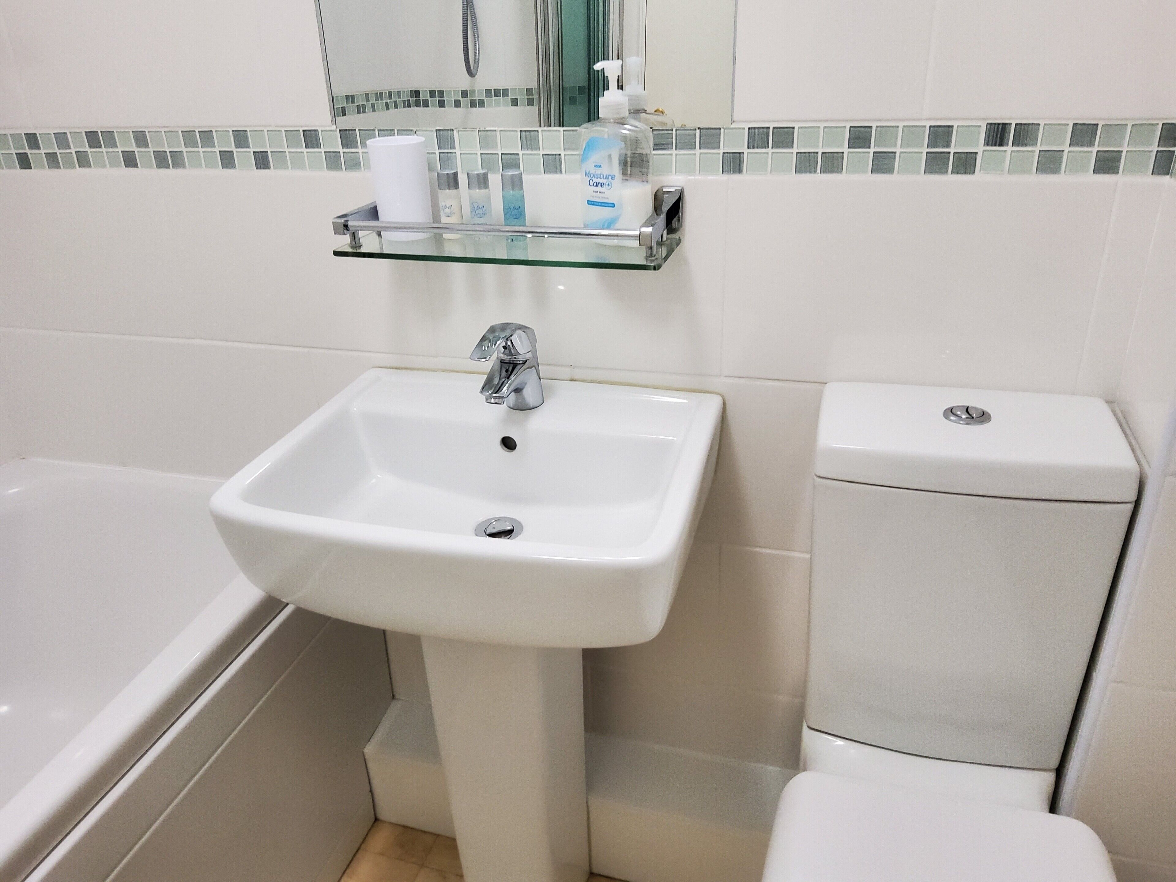 A bathroom with a white sink, a bathtub, and a toilet.