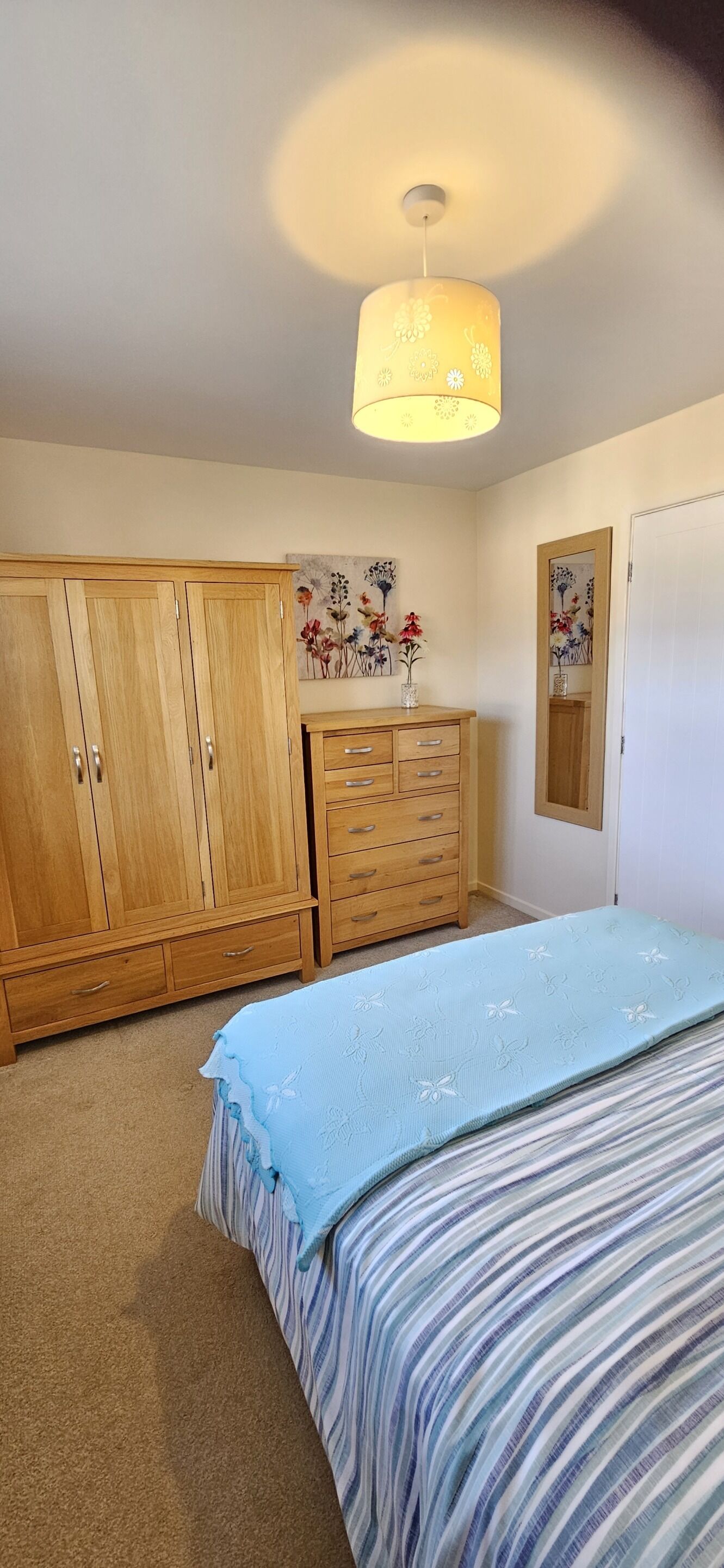 A bedroom with a bed, wooden wardrobe, and a dresser.