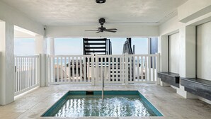 An indoor swimming pool with a ceiling fan, white railings, and a view of the ocean. - Beach House 3 · Ground Level · Door to Sand (Bradenton Beach)