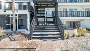 A multi-story building with a central staircase, outdoor seating, and a pool area. - Beach House 3 · Ground Level · Door to Sand (Bradenton Beach)