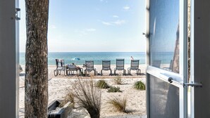 A beach view with a row of beach chairs and a palm tree. - Beach House 3 · Ground Level · Door to Sand (Bradenton Beach)