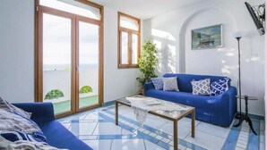 A living room with a blue sofa, a coffee table, and a view through large glass doors to a balcony.
