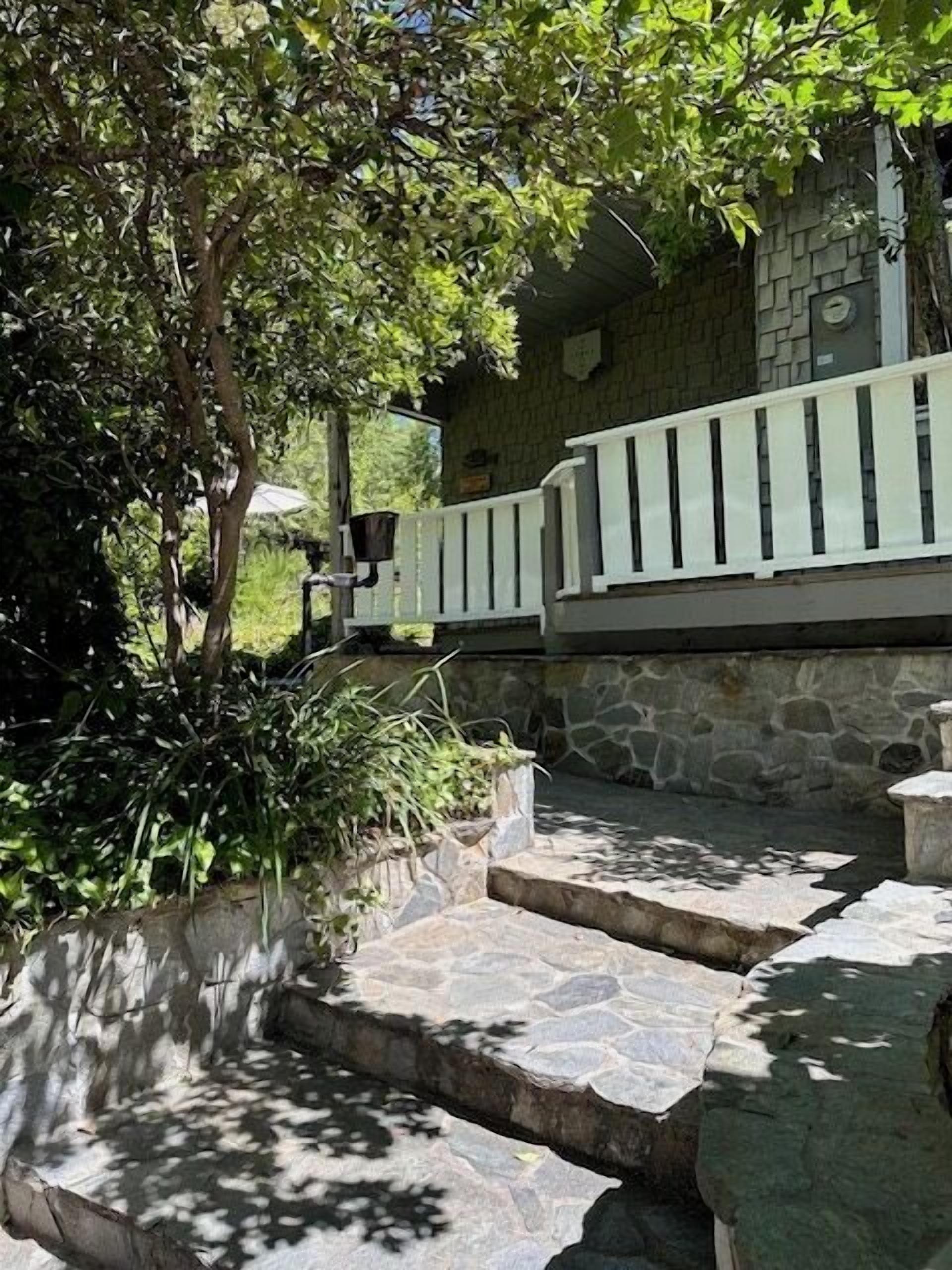 A stone staircase leading to a building with a stone wall and a white railing.