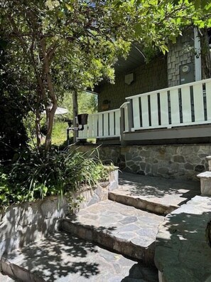 A stone staircase leading to a building with a stone wall and a white railing.