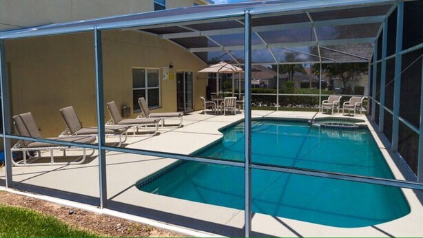 A covered outdoor swimming pool with lounge chairs and a patio area. - 7 Bed, 5 Bath. 15 Mins From Closest Disney Attractions (Orlando)