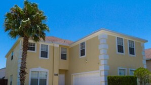 A two-story house with a garage, a palm tree, and a well-maintained lawn. - 7 Bed, 5 Bath. 15 Mins From Closest Disney Attractions (Orlando)