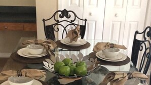 A dining table set for six with a glass top, surrounded by six chairs with metal frames. - 7 Bed, 5 Bath. 15 Mins From Closest Disney Attractions (Orlando)