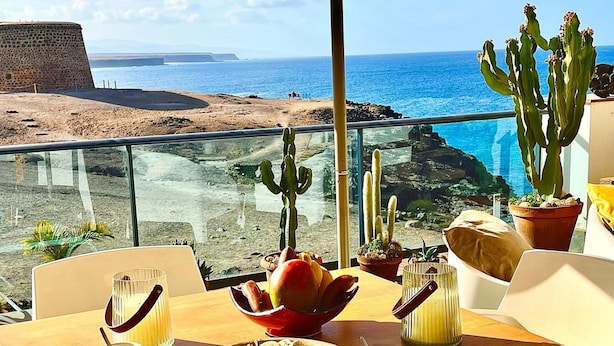 A dining table with a view of the ocean and rocky landscape. - Casa mar i sol El Cotillo (El Cotillo)