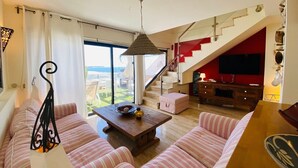 A living room with a sofa set, a coffee table, and a view of the sea through large windows. - Casa mar i sol El Cotillo (El Cotillo)