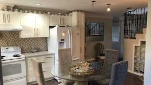 A modern kitchen with white cabinets, a glass dining table, and a built-in oven. - Royalty B&B (Richmond)