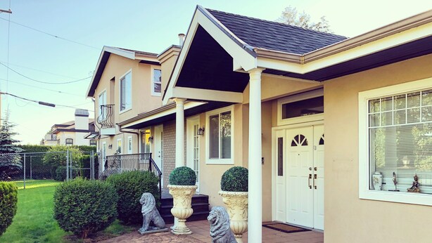 A two-story house with a covered porch, a front door, and a window with blinds. - Royalty B&B (Richmond)