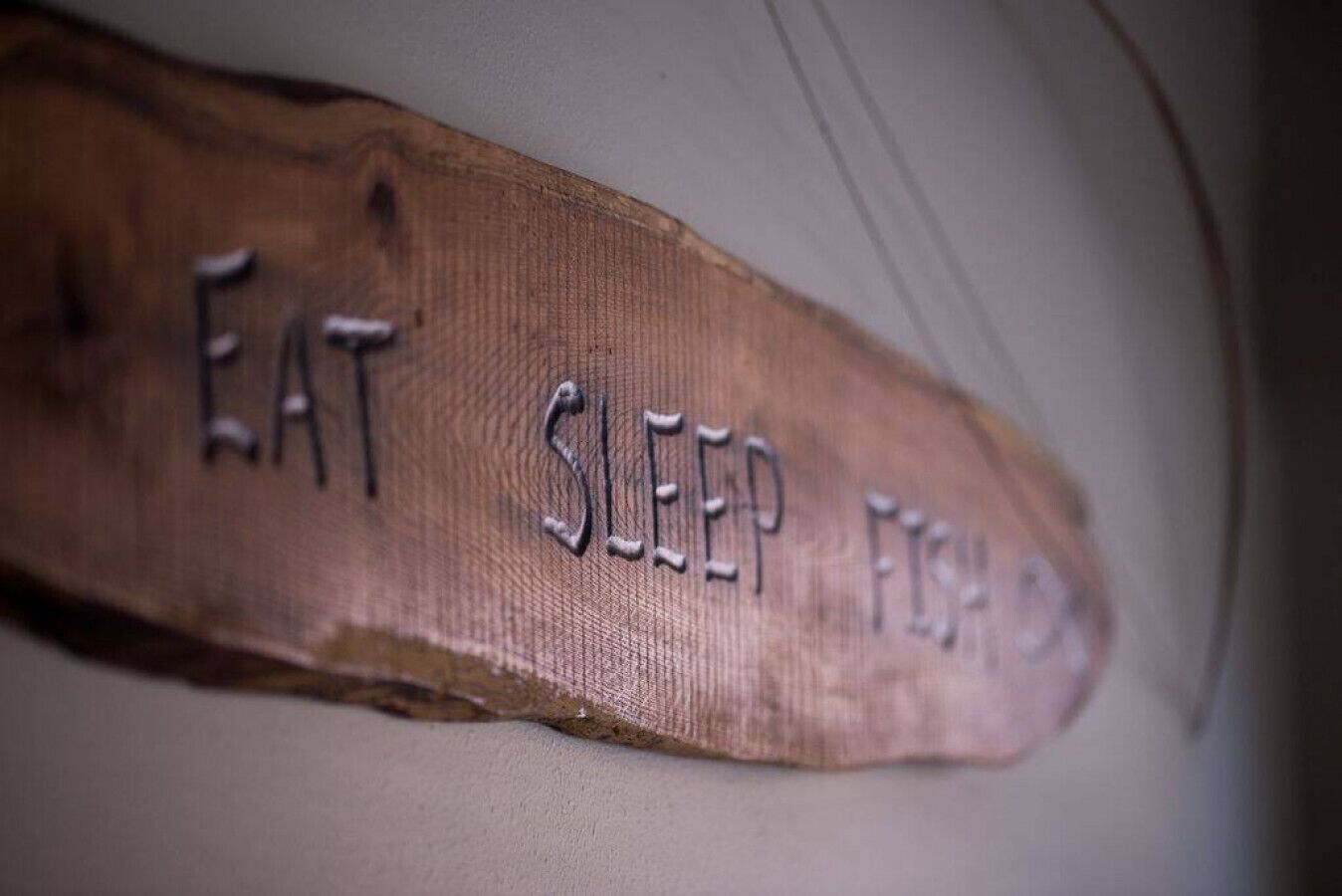 A wooden sign with the words "EAT SLEEP FISH" carved into it.