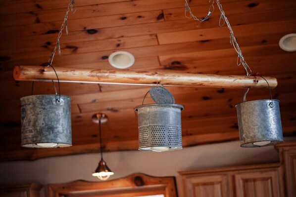 A rustic kitchen with wooden beams, a wooden ceiling, and three hanging metal containers.