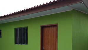 Ein Gebäude mit grüner Fassade, einer Holztür und einem Fliesenboden.