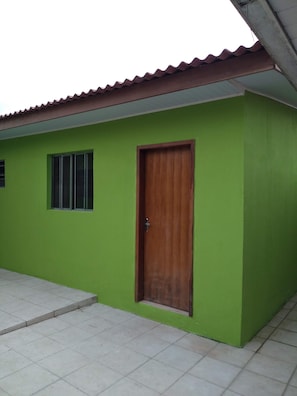 A building with a green exterior, a wooden door, and a tiled floor.