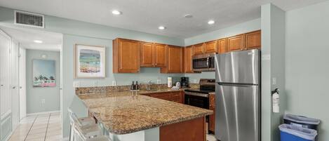 A modern kitchen with granite countertops, stainless steel appliances, and wooden cabinets.