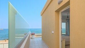 Un balcon offrant une vue dégagée sur la mer, un sol carrelé et une porte donnant sur une pièce.