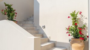 Un escalier avec un mur blanc et une grande plante en pot ornée de fleurs rouges.