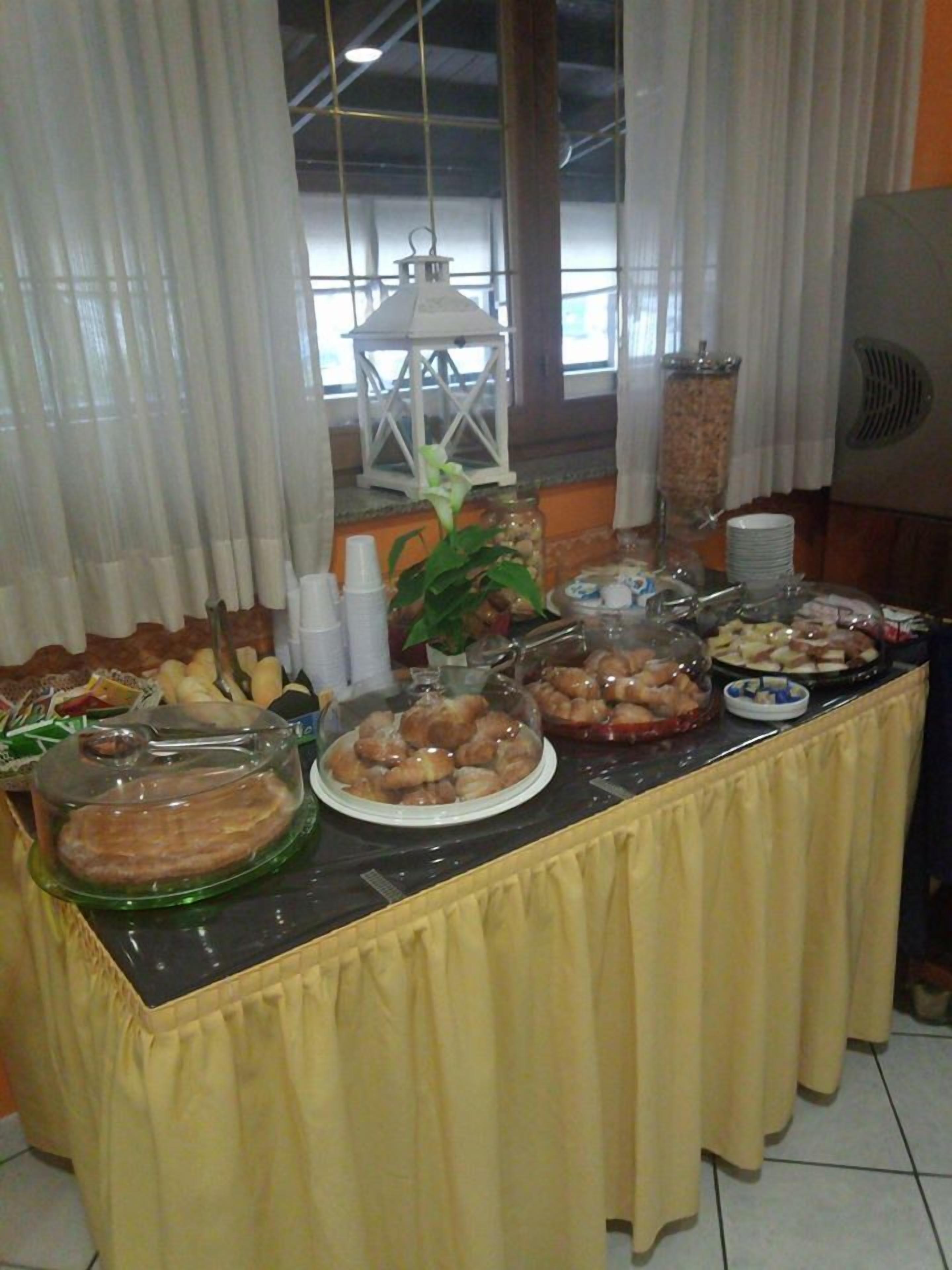 Una mesa de buffet con distintos alimentos, una planta en maceta y un farol colgante.