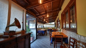 Un restaurante con mesas y sillas de madera, un tocadiscos antiguo y bombillas colgantes.