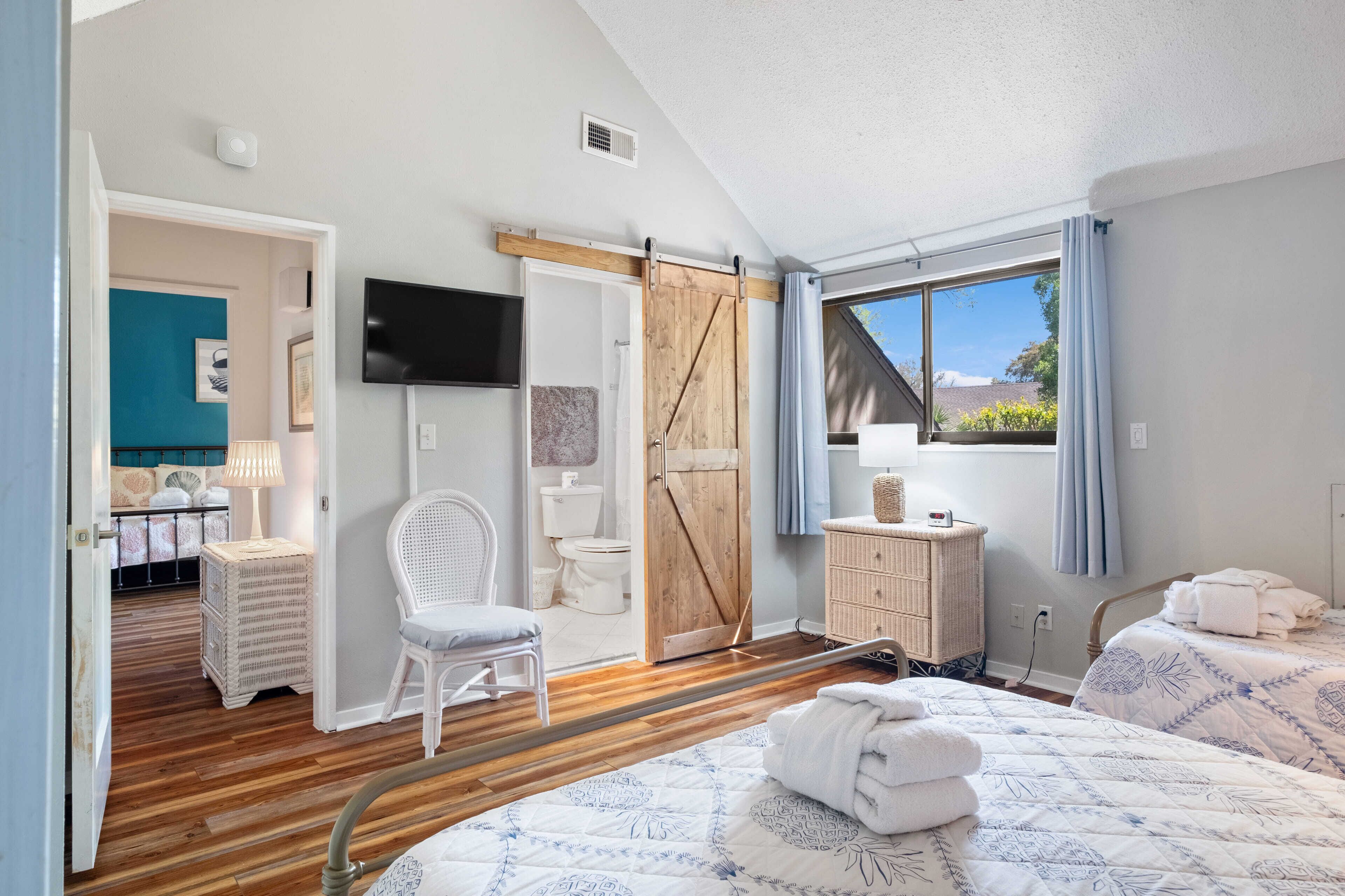 A bedroom with a bed, a chair, a dresser, and a TV.
