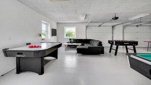 A spacious indoor recreational area with a foosball table, pool table, and billiards table.