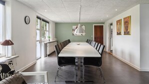 A conference room with a long table, chairs, a clock, and artwork on the walls.