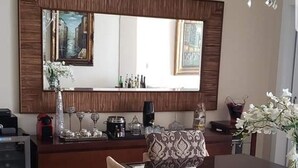 Un comedor moderno con un espejo grande, una araña y una mesa de comedor con sillas.