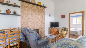 Un salon chaleureux avec un mur en briques, un téléviseur, un canapé, un fauteuil et une petite table.