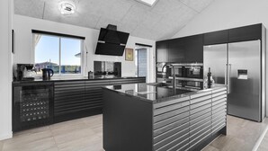A modern kitchen with a central island, built-in appliances, and a large window offering a view. - Stunning home in Hvide Sande with sauna (Hvide Sande)